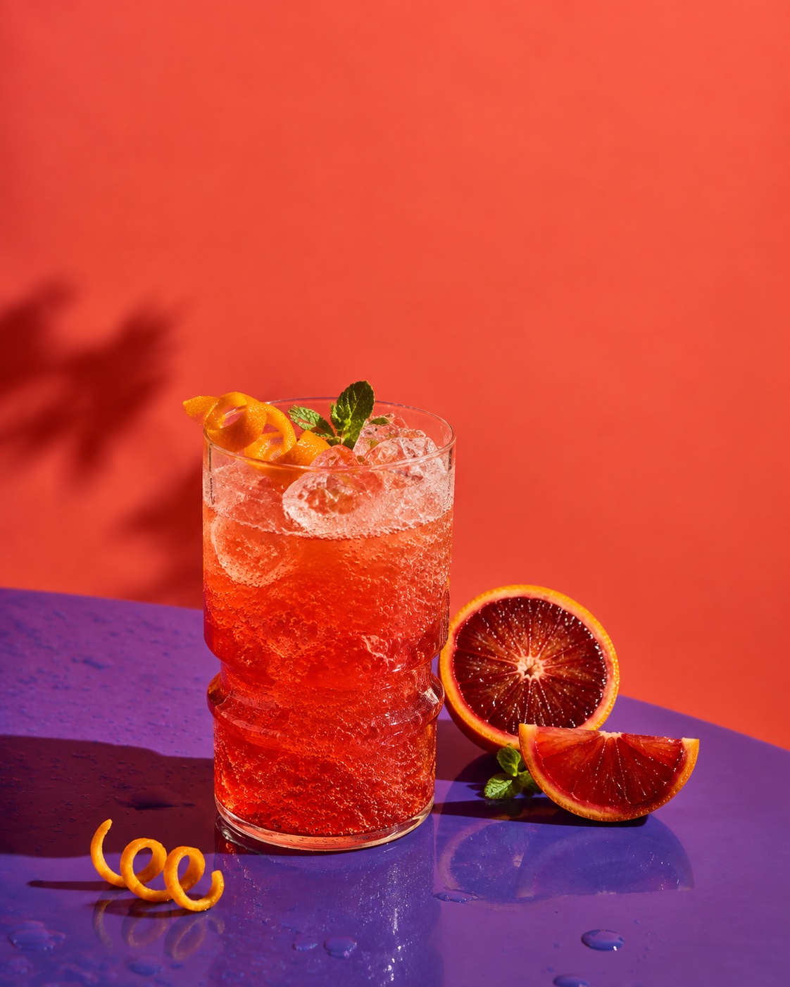 Original illustrative campaign photograph: sparkling blood-orange soda in warm afternoon light